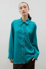 Camisa de corte holgado y diseño clásico, confeccionada en tela satinada con un sutil estampado floral tono sobre tono. Presenta cuello camisero, cierre frontal con botones y mangas largas con puños rectos.