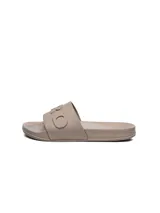 Ojotas tipo slide de mujer, color beige, con tira ancha que incluye relieve con la inscripción de la marca.