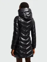 Campera larga de pluma Moncler modelo Marus, color negro con acabado brillante. Presenta un diseño acolchado con costuras en zigzag, capucha integrada, cierre frontal de cremallera y bolsillos laterales con cierre. Incluye el parche con el logo de la marca en la manga.