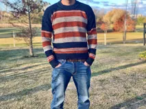 Sweater de lana merino a rayas horizontales en tonos azul marino, naranja y gris.