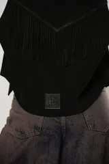 Chaleco negro de cuero descarne con terminación en picos, tachas metálicas y flecos en la espalda.