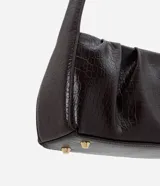 Cartera tipo baguette de material sintético con textura efecto crocco. Cuenta con asa fija de hombro, cierre superior con cremallera y base estructurada con pies metálicos dorados.