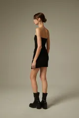 Vestido corto negro con apliques de strass, diseño ajustado al cuerpo, escote strapless y detalle drapeado en la parte frontal.