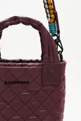 Cartera tote mini negra, con diseño matelasse y dos asas cortas. Incluye una correa larga ajustable y extraíble, con detalles de cuentas de colores.