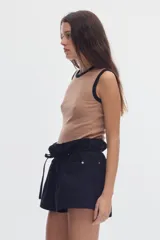 Musculosa de calce al cuerpo, en tejido rib color tostado, con cuello redondo y ribetes en contraste negros. Cuenta con un pequeño isotipo bordado en el centro del pecho.