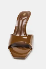 Mule de tacón alto, color marrón (café), con acabado acharolado brillante. Presenta una tira ancha en la parte delantera y punta cuadrada.