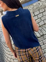 Top azul marino de gamuza con cuello buche y corte asimétrico, decorado con flecos diagonales en el frente.