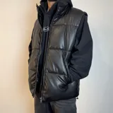 Chaleco puffer de cuero sintético en color negro, con diseño acolchado de paneles horizontales, cierre frontal completo y cuello alto.