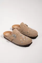 Suecos de cuero gamuzado color beige, con apliques metálicos y hebilla decorativa.