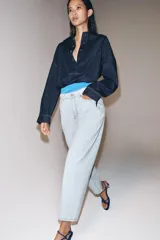 Jeans de tiro alto y silueta tapered, confeccionados en denim negro con costuras en tono contrastante. Cuenta con diseño de cinco bolsillos, trabillas para cinto y cierre frontal con cremallera y botón metálico.