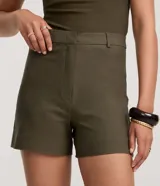 Short sastre de corte recto y tiro alto, confeccionado en bengalina de color verde militar, con trabillas en la cintura y cierre frontal tradicional.