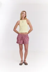 Top musculosa blanco de canalé con cuello redondo, corte ajustado y detalle de botones a presión en el lateral.