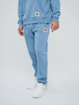 Pantalón jogger celeste de felpa, con cintura elástica ajustable con cordón, puños elastizados en los tobillos y un parche con el logo de la marca en la pierna izquierda.