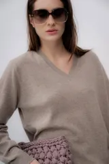 Sweater color beige de cashmere con escote en V y mangas largas.