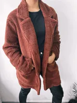 Saco largo color marrón chocolate, estilo teddy, con solapas y bolsillos laterales. Cierre frontal con botones. Talle único oversize.
