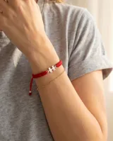 Pulsera de hilo rojo tejida en macramé con dijes de plata 925 en forma de niño y niña, con terminaciones ajustables decoradas con esferas de plata.
