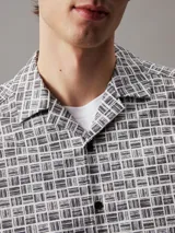 Camisa de hombre de manga corta con cuello cubano, corte boxy y estampado geométrico de rejilla en blanco y negro.
