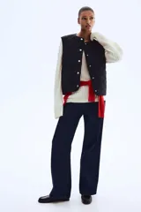 Chaleco de tejido guateado con diseño acolchado en forma de rombos, cuello redondo, cierre frontal con botones a presión y dos bolsillos delanteros de parche.