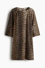 Vestido corto evasé con estampado de leopardo, escote redondo y abertura de cerradura con botón en la nuca. Mangas tres cuartos de corte raglán, pinzas en el busto y bajo recto.