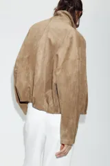 Chaqueta de efecto ante con cuello solapa envolvente, manga larga con hombro caído y bajo con elástico interior. Cuenta con bolsillos laterales ocultos en costura y forro interior.
