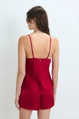 Conjunto de pijama de satén rojo, compuesto por un top de breteles finos con detalle de puntilla en el escote y un short con cintura elastizada y lazo ajustable.