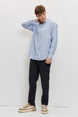 Camisa celeste de manga larga con cierre frontal de botones y cuello clásico.