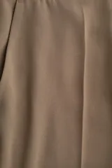 Pantalón de vestir color marrón, tiro alto, con pliegues marcados en la parte delantera y piernas rectas.