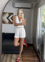 Mono corto negro con escote en V cruzado, sin mangas y con cinturón dorado.