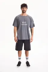 Remera gris de manga corta con lavado acid wash y diseño raglán con vivos en contraste. Presenta estampa frontal con el texto "WEST DIVISION" y número en la manga.