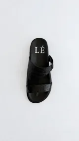Sandalias negras de cuero con textura simil cocodrilo, plantilla anatómica forrada y diseño de tiras cruzadas con hebilla lateral.