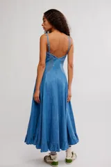 Vestido midi de denim azul, con silueta en línea A, escote corazón, tirantes finos y detalle de volados en el ruedo.