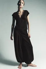 Pantalón bombacho de color marrón oscuro, confeccionado en lyocell 100%. Presenta tiro medio con cintura elástica, pliegues frontales, detalle de encaje a tono en el lateral y bajo abullonado con elástico.