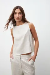 Top sin mangas de corte recto y holgado, con cuello redondo, confeccionado en tejido con acabado laminado plateado.