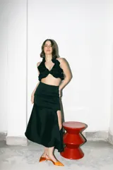 Falda midi negra de tafeta con leve tornasol, corte al bies, tajo lateral y volado en el ruedo.