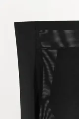 Shorts de tiro alto, color negro, confeccionado en tejido semitransparente de poliamida. La cintura es elástica y el bajo está rematado con una aplicación de encaje en tono beige/dorado.