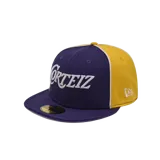 Gorra tipo cap de visera plana, colaboración entre Corteiz y New Era. Presenta un diseño bicolor en violeta y amarillo, con el logo de Corteiz bordado en blanco en el frente y el logo de New Era en el lateral.