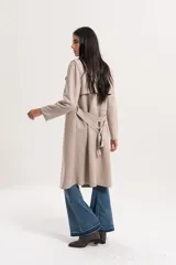 Trench largo de gamuza en color beige, con solapas amplias, diseño abierto y corte recto.