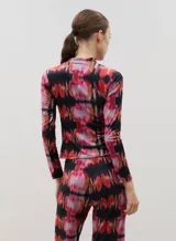 Polera de manga larga con cuello alto, confeccionada en tela sublimada con estampado abstracto en tonos rojizos, rosados y negros.
