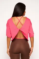 Remera corta de manga corta color celeste, con escote amplio en la espalda que se anuda en la parte inferior, dejando ver un top deportivo amarillo con tiras cruzadas.