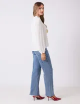 Blusa azul de gasa con pliegues en la parte delantera y detalles de encaje calado. Cuello alto fruncido y mangas largas con puños elastizados. Espalda lisa con abertura tipo gota y botón.