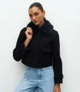 Saco corto de polivelour negro con cuello de piel sintética, cierre frontal oculto, bolsillos cargo delanteros con solapa y detalles de botones en los puños.