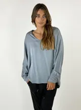 Blusa celeste de seda suelta con mangas largas y puños elásticos.