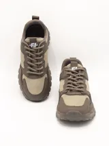 Zapatillas urbanas de estilo trekking, color taupe (marrón claro/beige), con suela gruesa y detalles superpuestos en material sintético y textil.