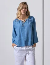 Blusa celeste de lyocell con cuello a la base y escote en V con lazo de ajuste. Manga larga amplia.