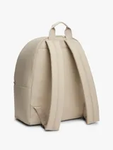 Mochila Tommy Jeans Essential Dome de tejido ripstop en color beige, con diseño curvo, compartimento principal con cierre de cremallera, bolsillo exterior frontal con cremallera, asa superior y correas ajustables y acolchadas. Incluye parche con el logo de la marca en el bolsillo frontal.