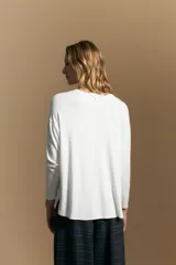 Remera de manga larga con silueta relajada y caída fluida, confeccionada en tejido suave con cuello redondo y aberturas laterales en el ruedo.