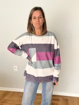 Remera de manga larga en tejido liviano con diseño de rayas anchas en tonos fucsia, gris y crudo. Corte recto y cómodo con bolsillo delantero.