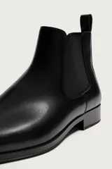 Bota Chelsea de hombre en color marrón oscuro, con diseño liso, punta afilada, elásticos laterales y tirador trasero.