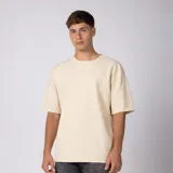 Remera oversized de algodón grueso con textura micropanal, color beige, de cuello redondo y manga corta, con costura decorativa en "X" en el escote y diseño liso sin logos.