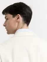Saco de lino color beige, de corte clásico, con solapas de muesca, cierre de dos botones y bolsillos de parche.